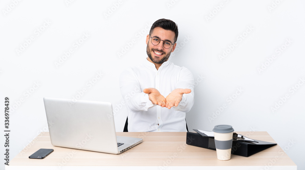Young businessman in a workplace holding copyspace imaginary on the palm to insert an ad Young businessman in a workplace holding copyspace imaginary on the palm to insert an ad
