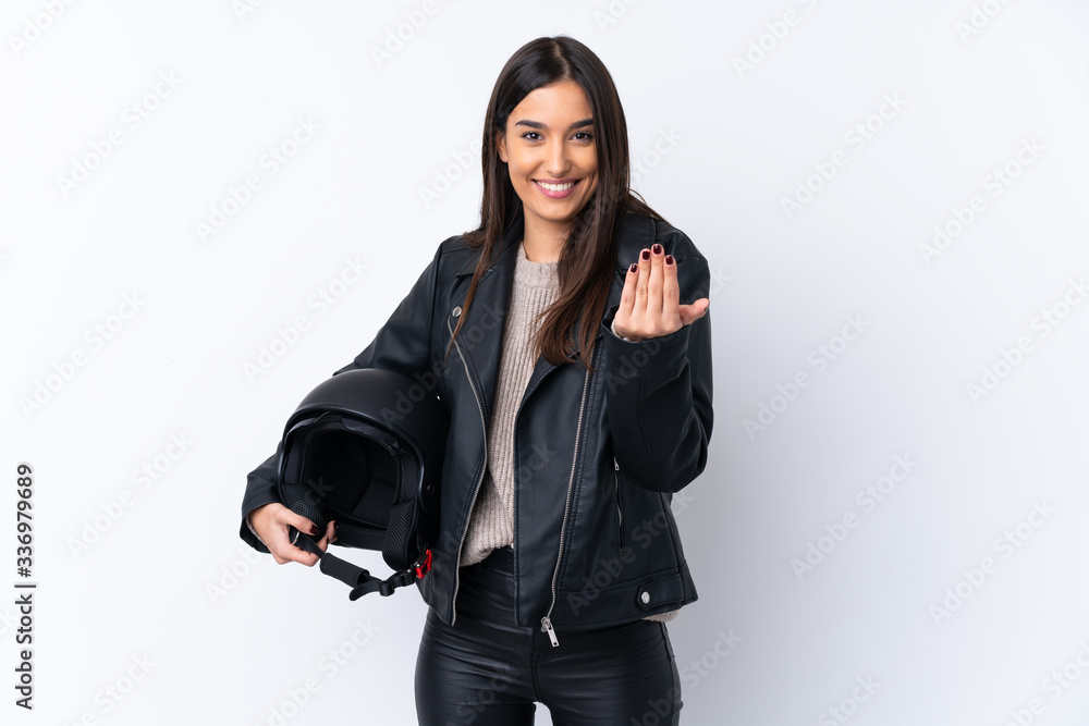 Young brunette woman with a motorcycle helmet over isolated white background inviting to come with hand. Happy that you came Young brunette woman with a motorcycle helmet over isolated white background inviting to come with hand. Happy that you came