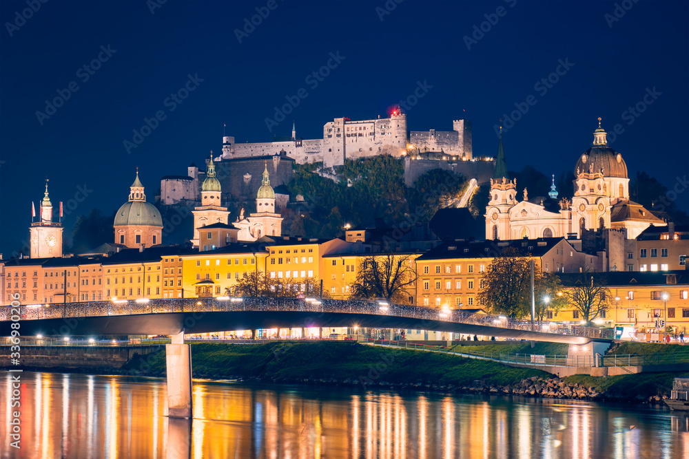 Salzburg city evening view. Cathedral, Old Town Altstadt, Hohensalzburg castle illuminated at night. Salzach River waterfront with promenade. Salzburg, Austria