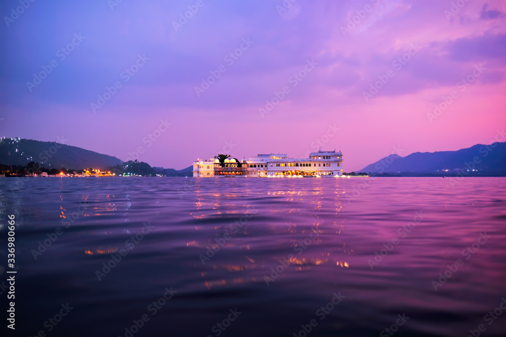 Fototapeta Romantic luxury India travel tourism - Lake Palace (Jag Niwas) complex on Lake Pichola on sunset in twilight with dramatic sky, Udaipur, Rajasthan, India