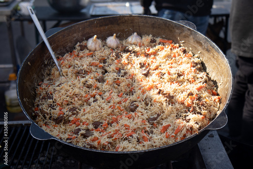 Cooking of traditional pilaf in big cauldron, street food in outdoor