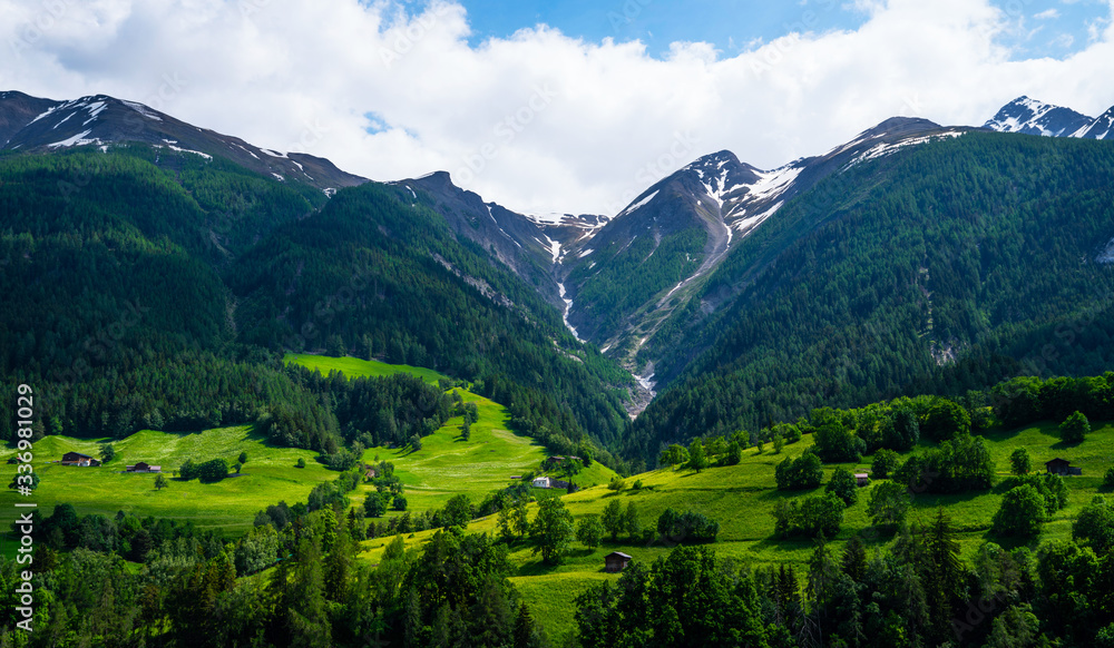 Mountain range. Beautiful view of alpine meadows in the Swiss mountains. Pastures, meadows on the slopes and snow-capped mountains.