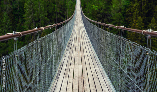 Fototapeta Naklejka Na Ścianę i Meble -  View of suspension bridge in Swiss Alps. Suspension bridge, crossing the river, crossing in the woods.