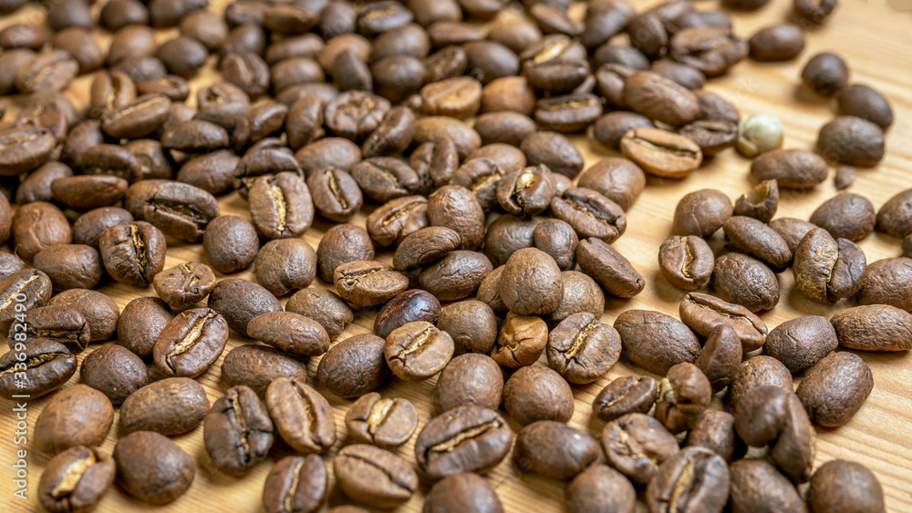 Roasted coffee beans randomly dumped on a wooden table-Close up Roasted coffee beans randomly dumped on a wooden table-Close up