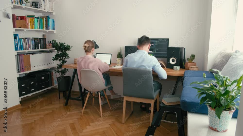Couple or Partners Work in Home Office at Computer and Laptop at Daytime. Video Editor, Bloggers or Freelancers Work Remotely in Cozy Room. Family or Spouses Work Together. 4K Wide Static Shot Couple or Partners Work in Home Office at Computer and Laptop at Daytime. Video Editor, Bloggers or Freelancers Work Remotely in Cozy Room. Family or Spouses Work Together. 4K Wide Static Shot