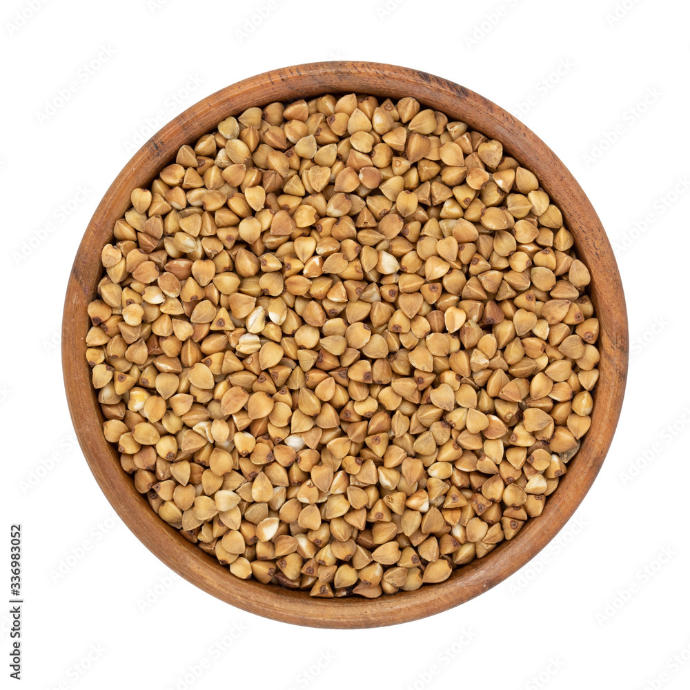 Uncooked buckwheat in wooden bowl isolated on white background. Top view. Uncooked buckwheat in wooden bowl isolated on white background. Top view.