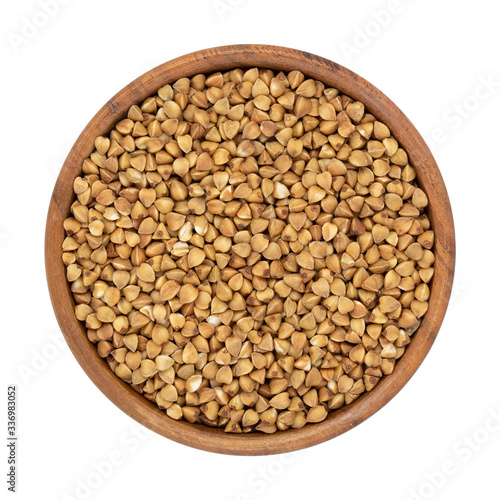 Uncooked buckwheat in wooden bowl isolated on white background. Top view.