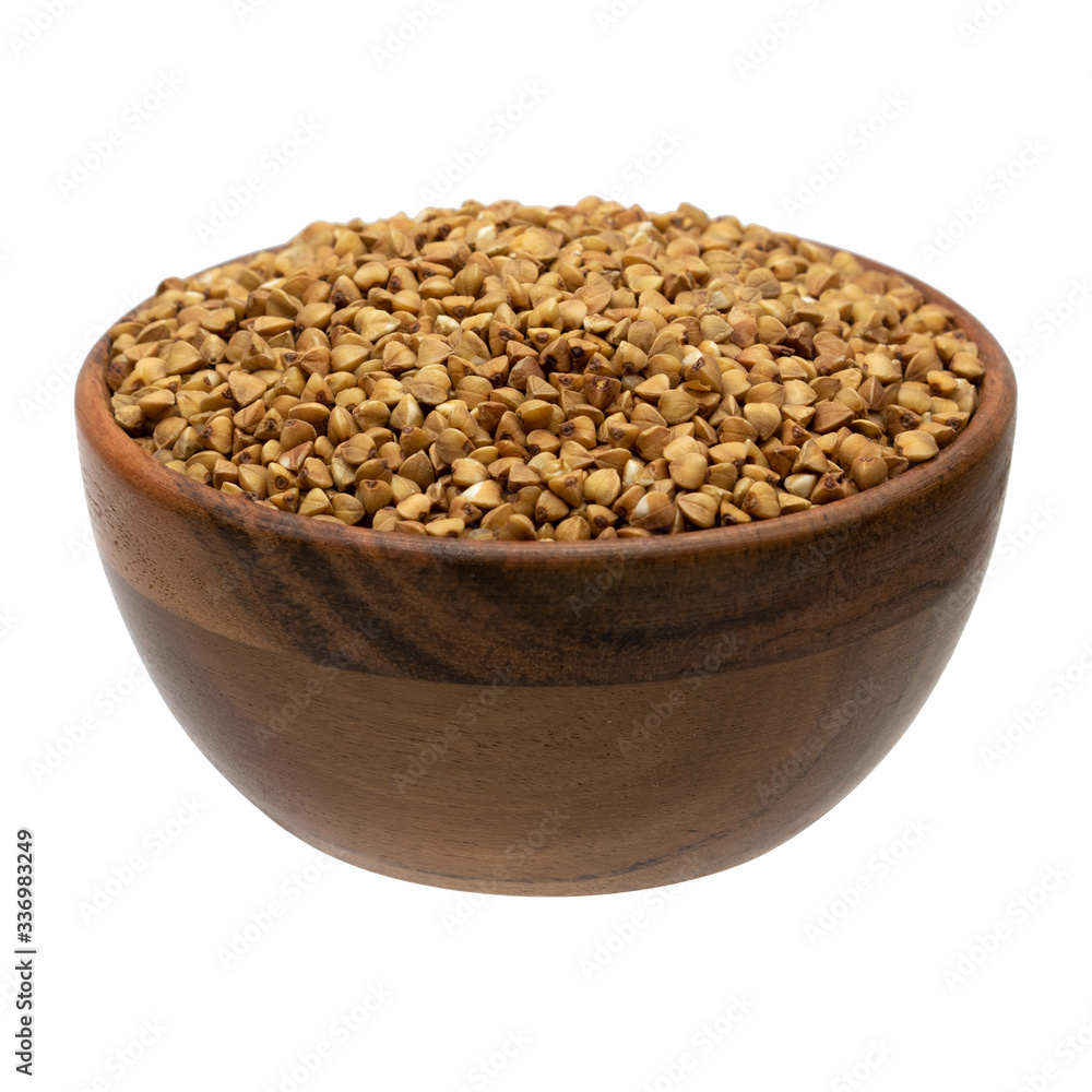 Uncooked buckwheat in wooden bowl isolated on white background.