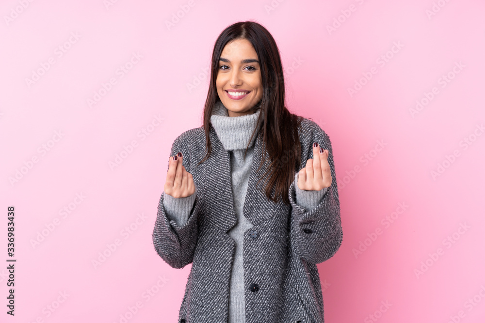Fototapeta premium Young brunette woman over isolated pink background making money gesture