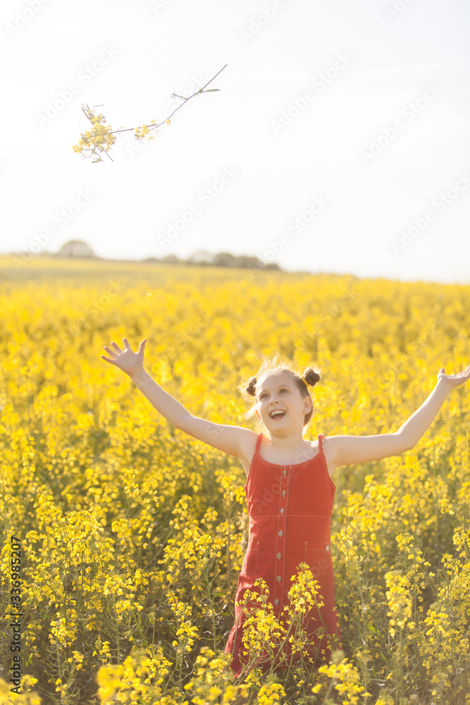 Cute girl in a red dress having fun in the field of flowering rape Cute girl in a red dress having fun in the field of flowering rape