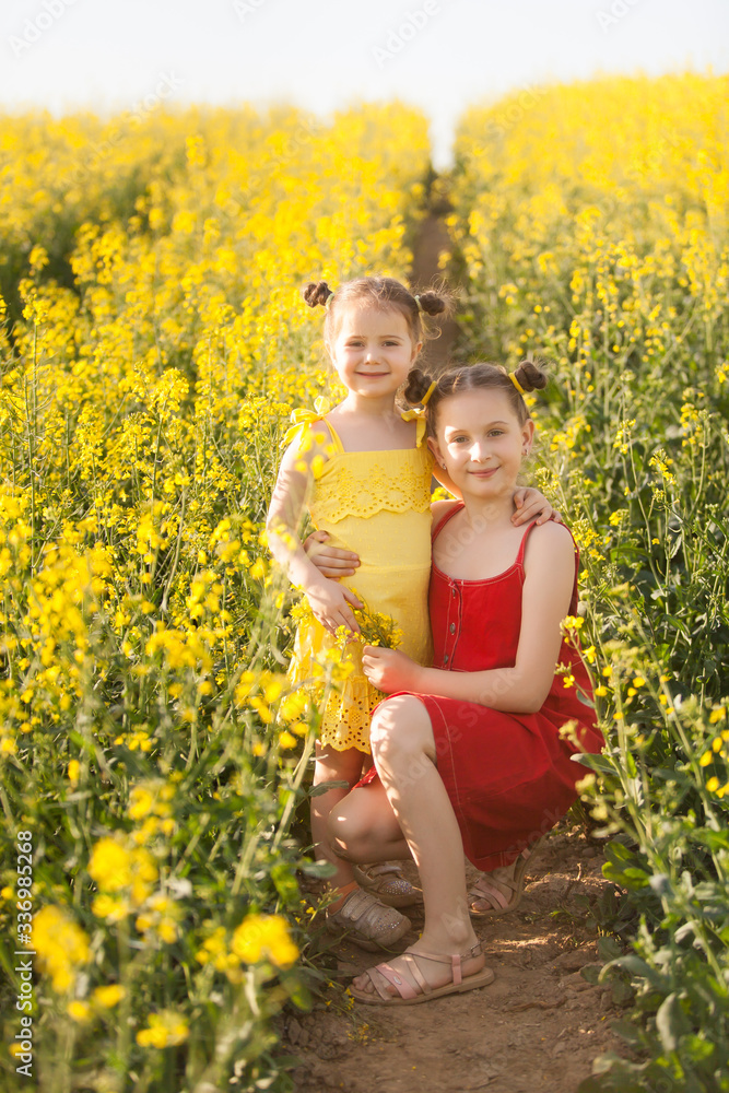Cute girls in yellow dresses having fun in the field of flowering rape Cute girls in yellow dresses having fun in the field of flowering rape