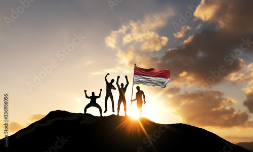 A group of people celebrate on a mountain top with Indonesia flag. 3D Render