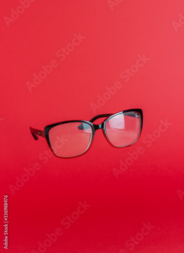 Reading glasses on a red background. Levitation. Design. Mock-up. Copy space. Minimal concept.