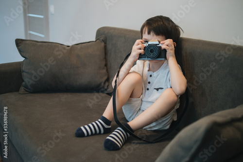 Beautiful smiling child (kid, boy) - photographer holding a instant camera intdoors photo