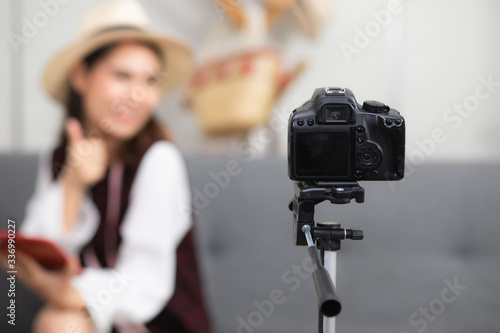 A digital dslr camera was placed on a tripod, shooting a beautiful Asian woman in the living room in the residence. In the concept of shooting video reviews of bloggers or product reviewers