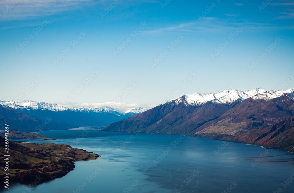Stunning aerial image of the Wanaka lake with the snowy Mount Aspiring in the background on a sunny winter day, New Zealand Stunning aerial image of the Wanaka lake with the snowy Mount Aspiring in the background on a sunny winter day, New Zealand