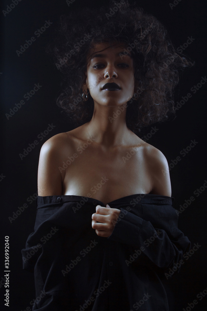 Beautiful afro american girl with curly hair posing in studio on dark background. Beautiful afro american girl with curly hair posing in studio on dark background.