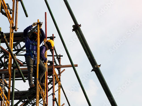 Construction workers working on scaffolding, Man Working on the Working at height with blue sky at construction site