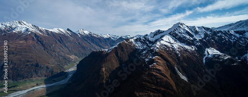 Stunning aerial image of the mouth of the glacier at Lake Wanaka surrounded by snow capped mountains taken on a sunny winter day, New Zealand