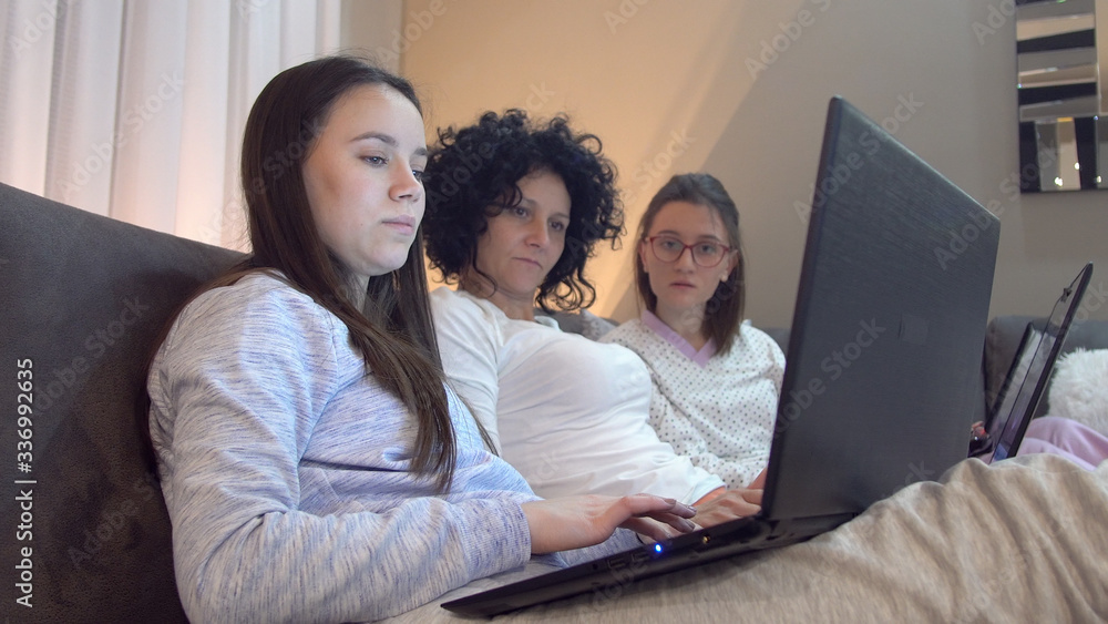 Relaxed family using laptop sitting on sofa, checking news in social networks, chatting with friends or working, learning on computer, social distancing and distance working and education