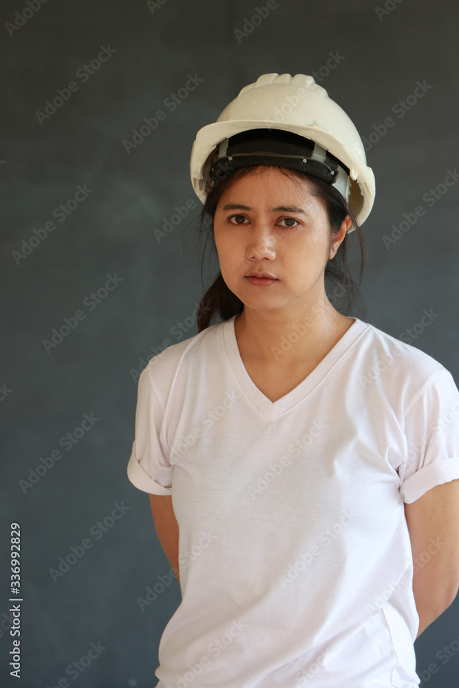 Female civil engineer with white helmet and wear white T-shirt on dark grey background. Female civil engineer with white helmet and wear white T-shirt on dark grey background.