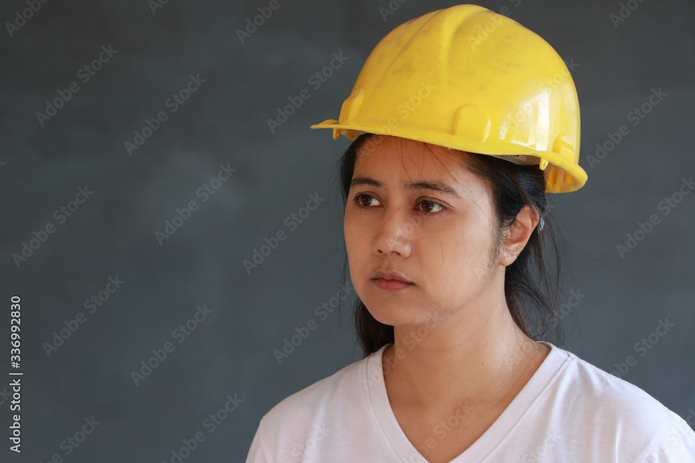 Female civil engineer with yellow helmet and wear white T-shirt on dark grey background. Female civil engineer with yellow helmet and wear white T-shirt on dark grey background.
