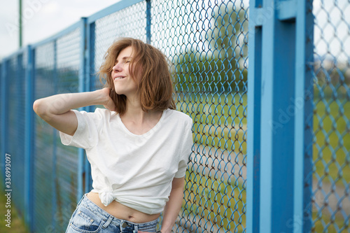 sensual portrait of redhead skinny caucasian girl standing near fence