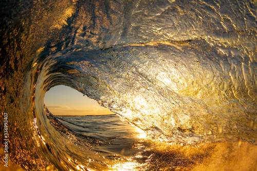 golden sunset over the ocean from inside a wave © Sacha Specker