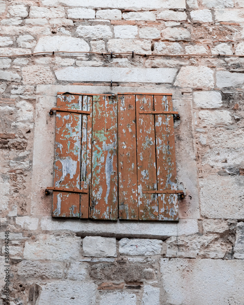 Old brick house with windows protected by closed brown wooden shutters. Old brick house with windows protected by closed brown wooden shutters.