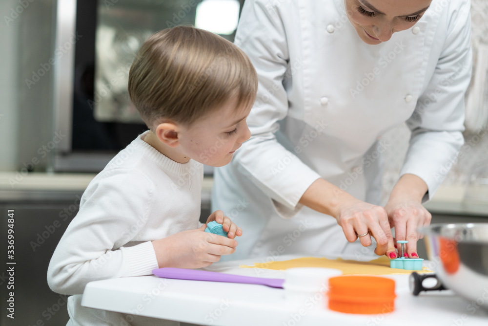 Little blond boy preparing Christmas cookies with her mother. Little blond boy preparing Christmas cookies with her mother.