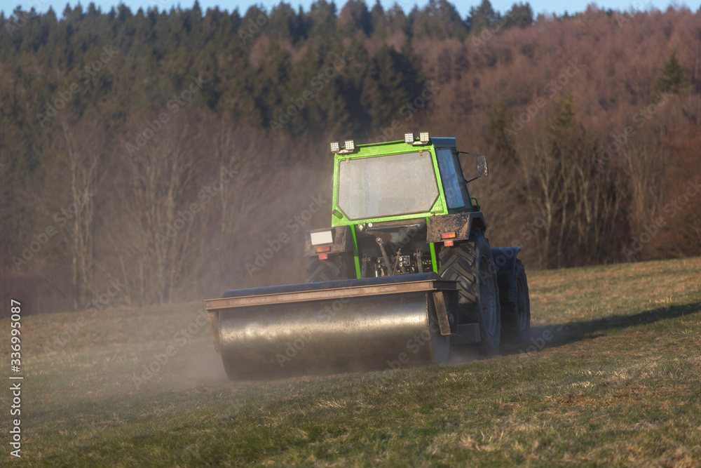 Fototapeta premium a tractor on a meadow in the evening