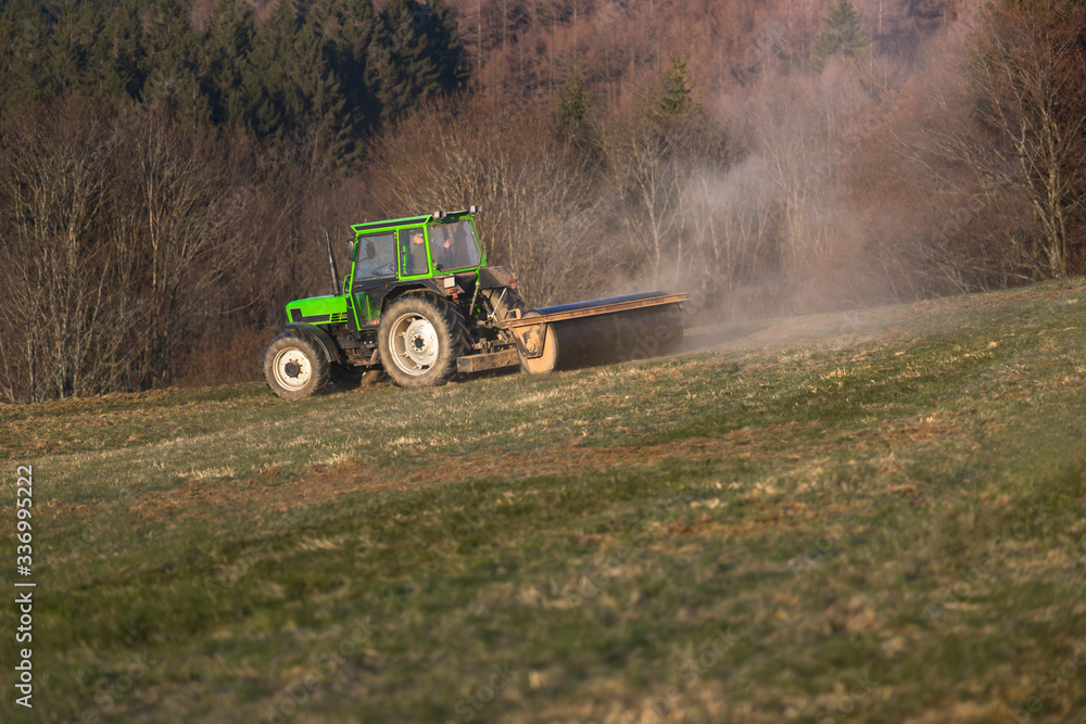 Fototapeta premium a tractor on a meadow in the evening