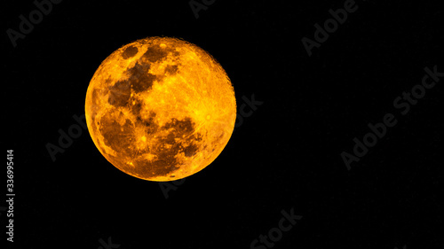 Gros plan d'une super pleine lune jaune orangée au-dessus la Guadeloupe en début de soirée dans un ciel totalement dégagé