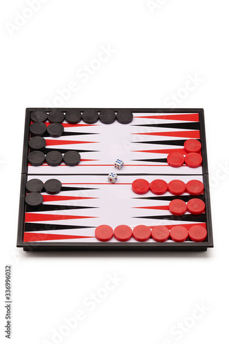 Subject shot of backgammon on the white backdrop. The narde set consists of a folding board, black and red playing chips and two cubes.  photo