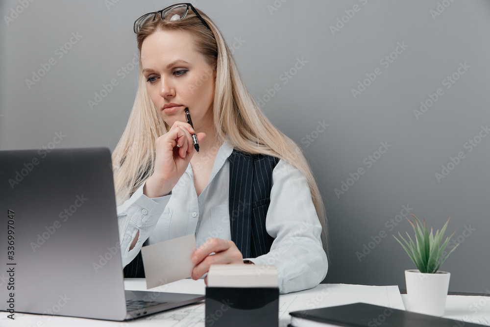 Young beautiful business girl takes some notes in a notebook while sitting in her workplace Young beautiful business girl takes some notes in a notebook while sitting in her workplace