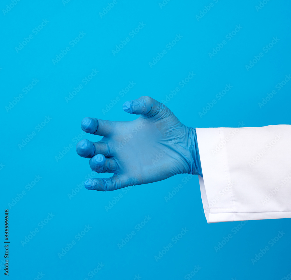 doctor’s hand is wearing a blue sterile rubber glove holding an object, blue background