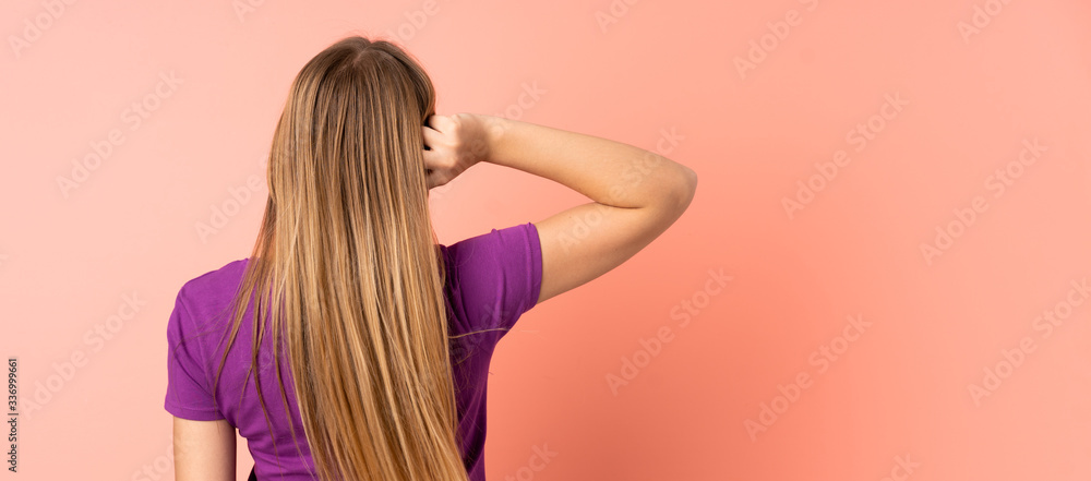 Teenager Ukrainian girl isolated on pink background in back position and thinking Teenager Ukrainian girl isolated on pink background in back position and thinking