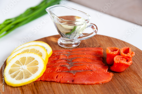 Slice of pink salmon fish on a slice of bread and fresh lemon on the wooden plate