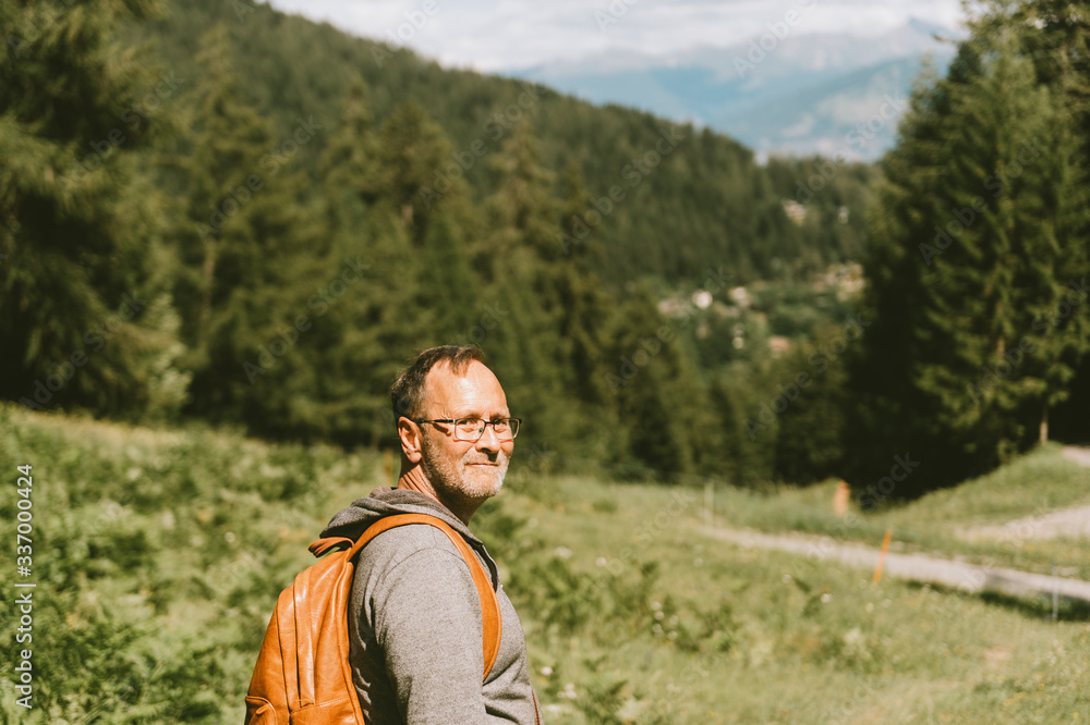 Outdoor portrait of middle age man hiking in mountains, wearing backpack, active lifestyle