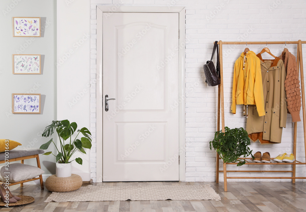 Hallway interior with stylish furniture, clothes and plants