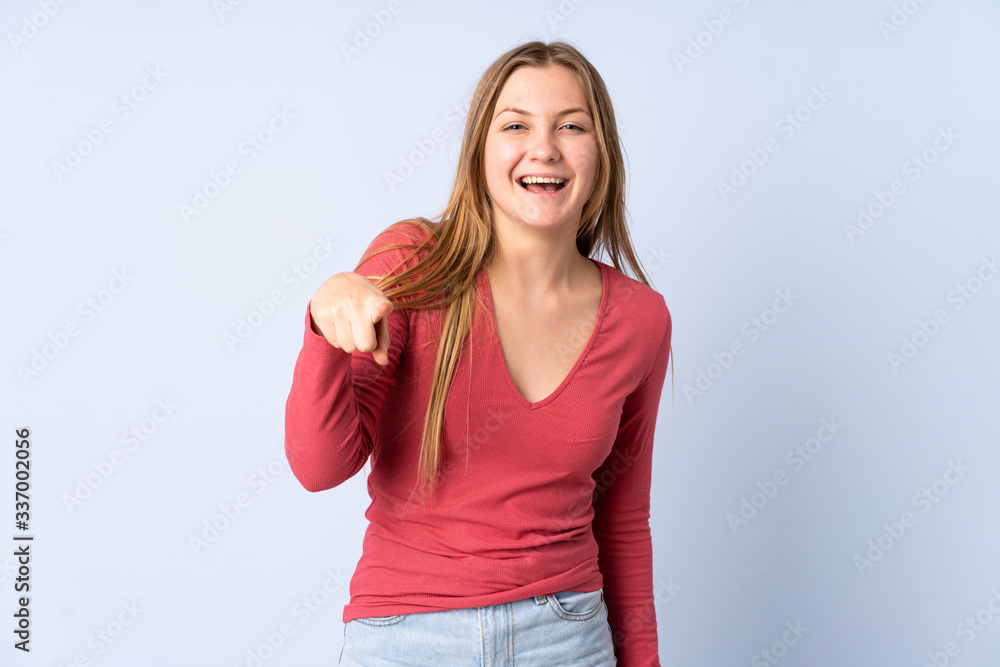 Teenager Ukrainian girl isolated on blue background surprised and pointing front Teenager Ukrainian girl isolated on blue background surprised and pointing front