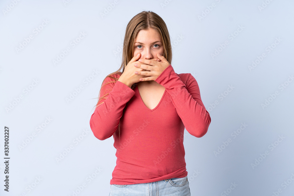 Teenager Ukrainian girl isolated on blue background covering mouth with hands Teenager Ukrainian girl isolated on blue background covering mouth with hands