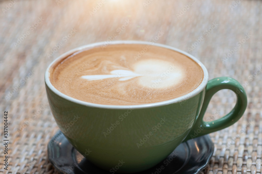 Obraz premium Hot cappuccino coffee with steam fresh milk serve with green cup on rattan mat.