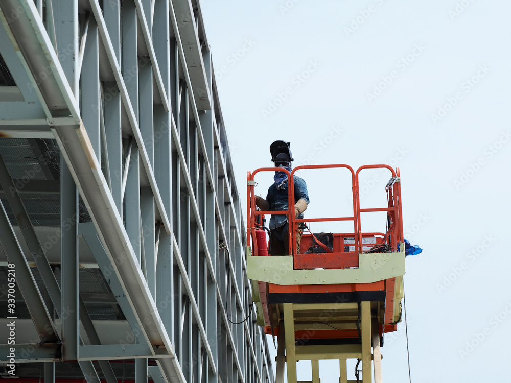 construction worker at construction site using lifting boom machinery