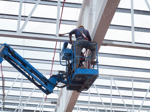 construction worker at construction site using lifting boom machinery photo