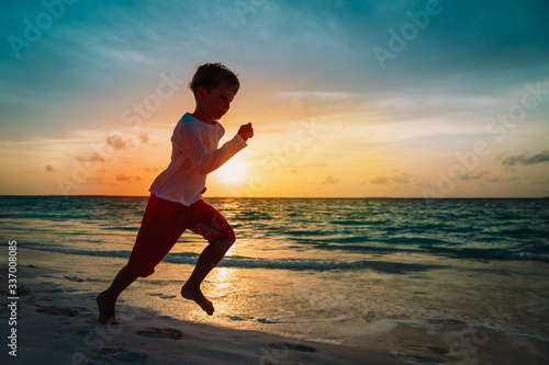 happy little boy run on sunset beach