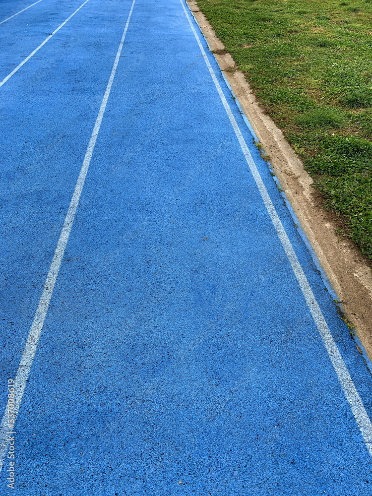 Fototapeta premium blu running racetrack in the grass field