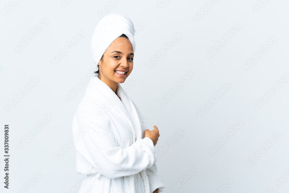Young woman in bathrobe over isolated white background pointing back Young woman in bathrobe over isolated white background pointing back