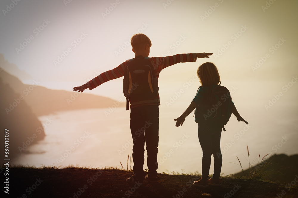 Fototapeta premium happy boy and girl travel in mountains at sunset