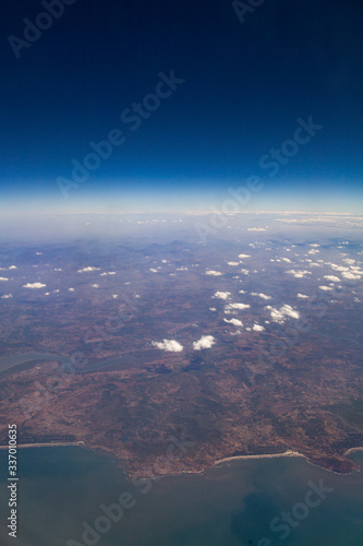 Beautiful clouds top view on a background of blue sky from the porthole of an airplane at altitude.